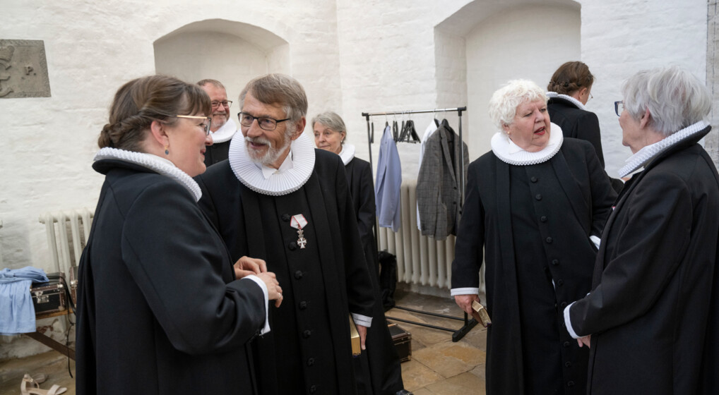 Præster i præstekjole taler glade sammen inden gudstjeneste